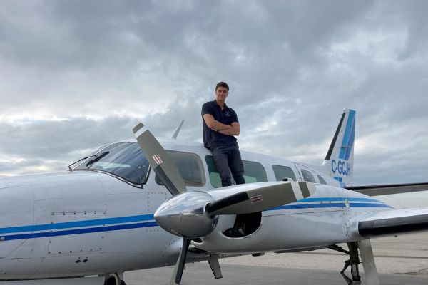 91̽ alum Joey Rood standing by an airplane